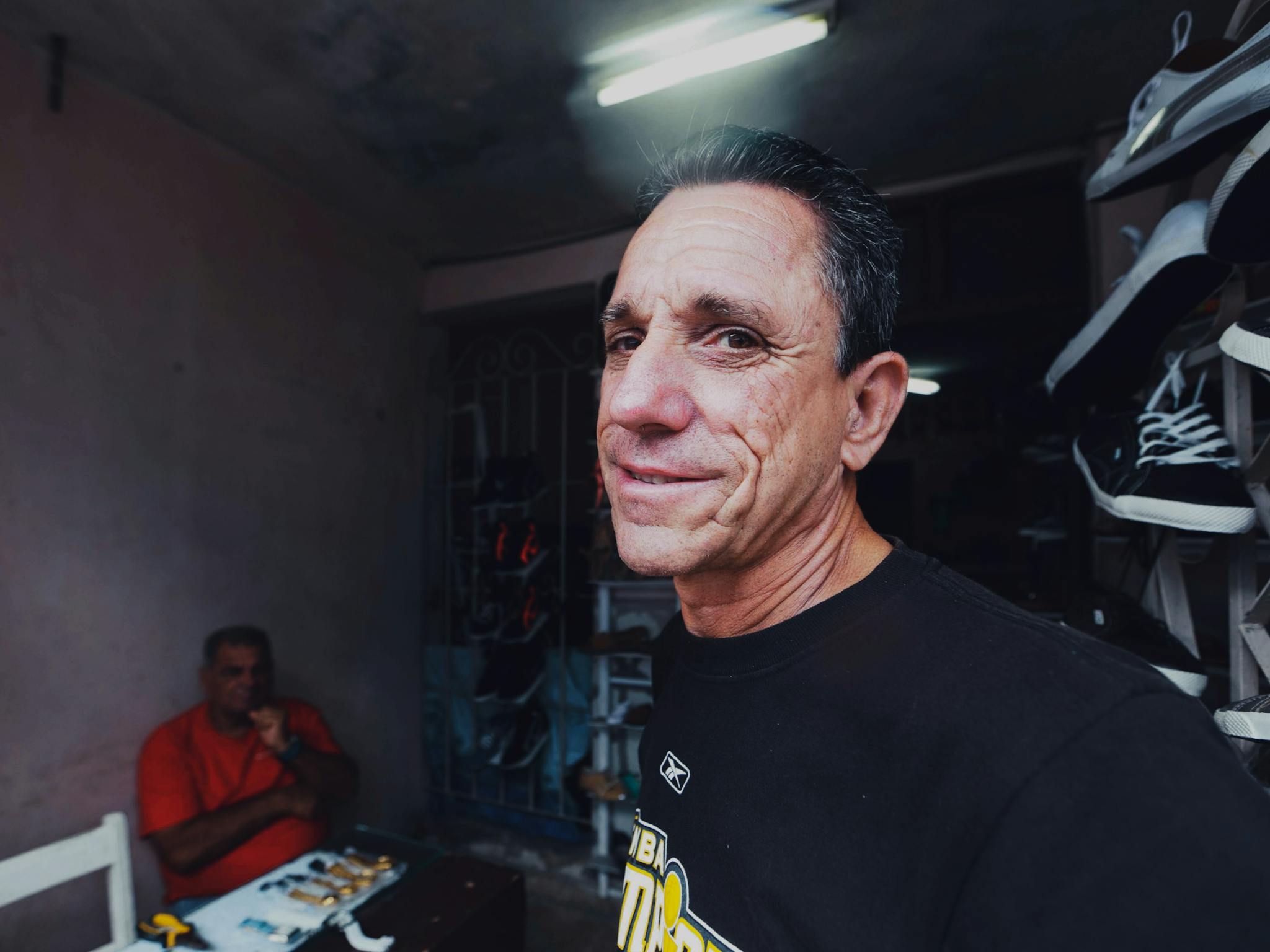 Elderly man smiling indoors at a shoe store with vibrant lighting.
