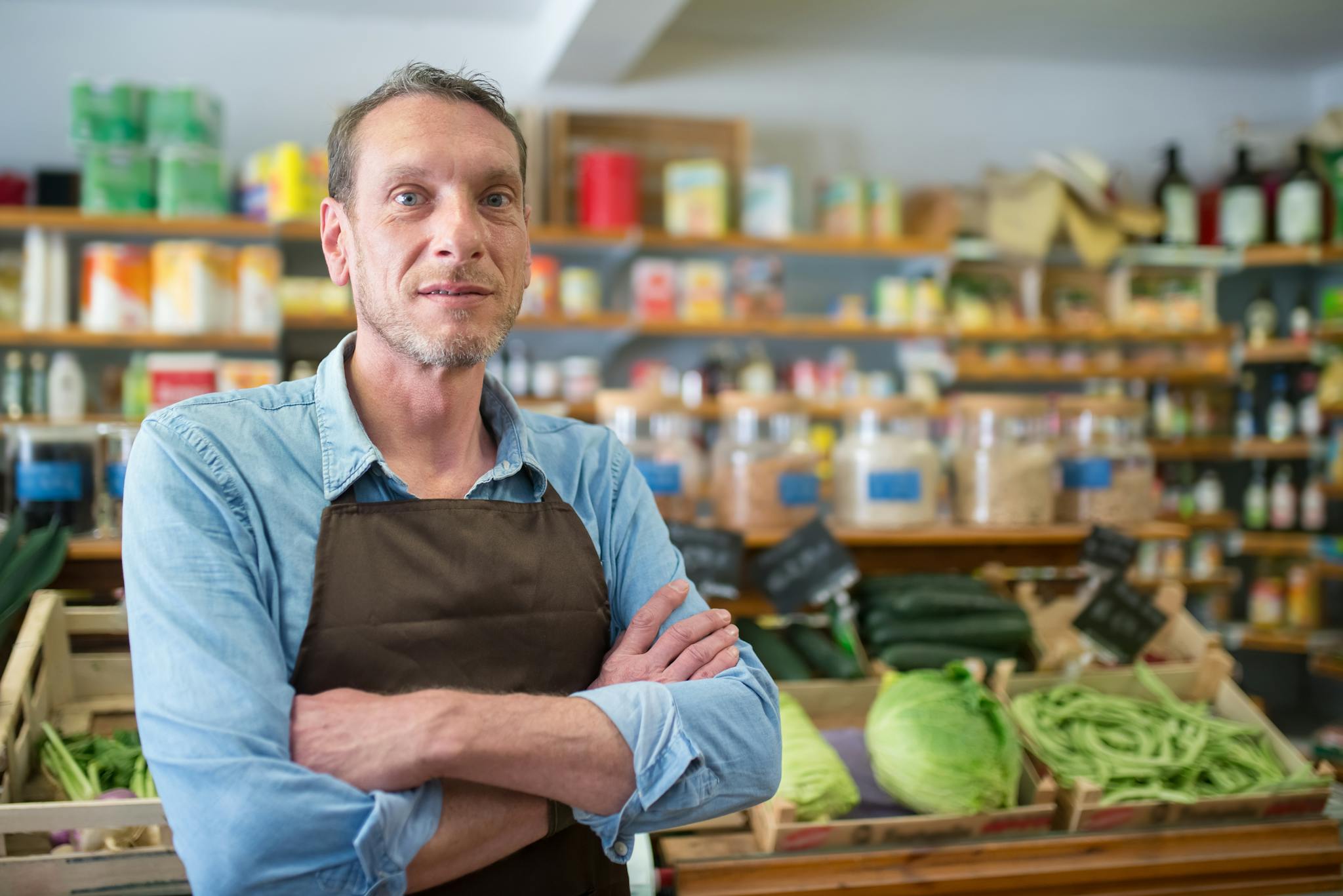 Portrait of a male vendor in a Portuguese grocery store with fresh produce.