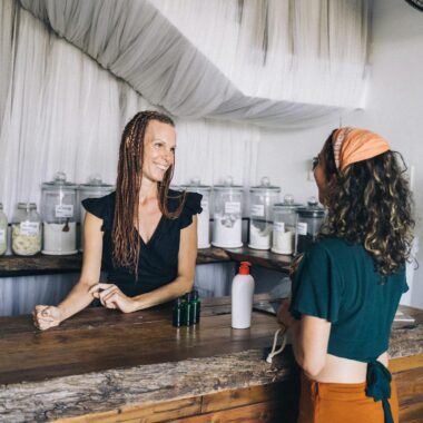 Smiling shopkeeper and customer at eco-friendly zero waste store counter.