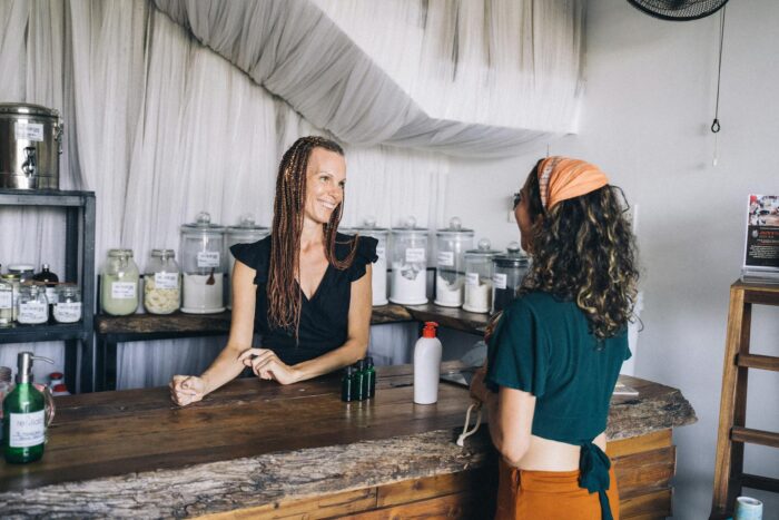 Smiling shopkeeper and customer at eco-friendly zero waste store counter.